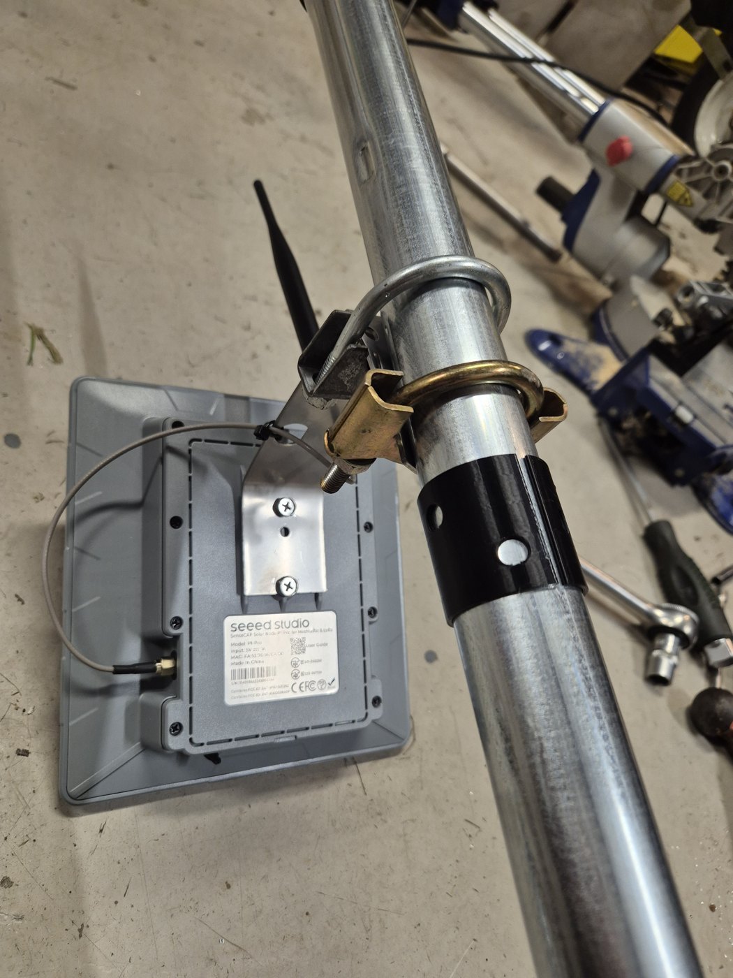 Detail of a homemade mast with clamps, mounting and electronics enclosure.